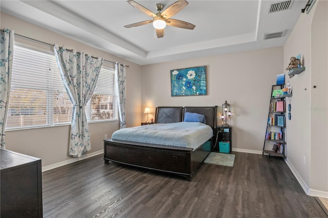 bedroom featuring a tray ceiling, wood finished floors, and visible vents