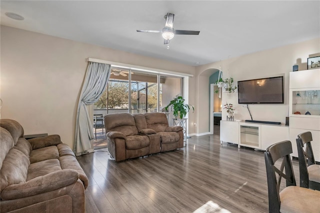 living area featuring a ceiling fan, baseboards, arched walkways, and wood finished floors