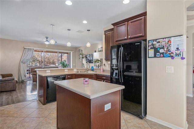 kitchen featuring a peninsula, a sink, open floor plan, light countertops, and black appliances