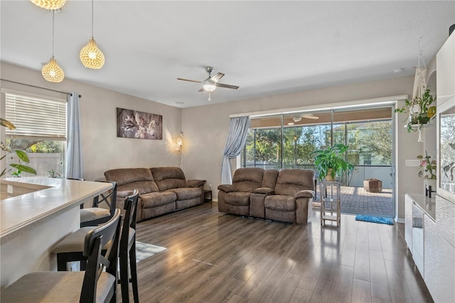 living room featuring wood finished floors, a ceiling fan, and baseboards