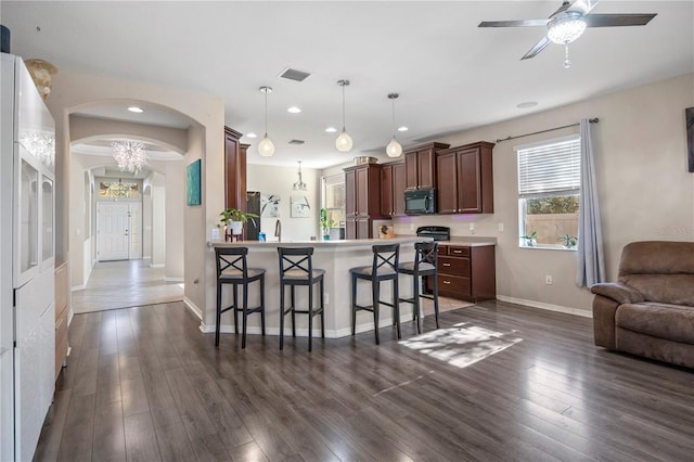 kitchen featuring visible vents, dark wood finished floors, a breakfast bar, open floor plan, and black microwave