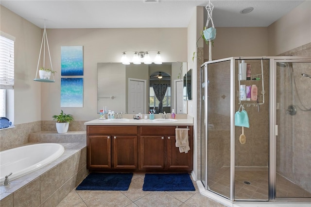 bathroom with a bath, tile patterned flooring, a shower stall, and a sink