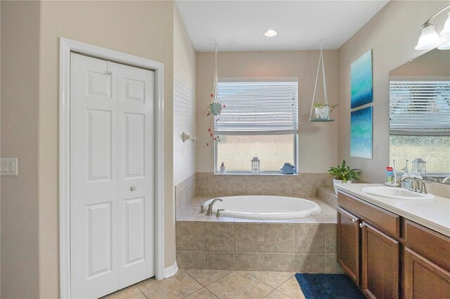 full bathroom with a closet, vanity, a bath, and tile patterned floors