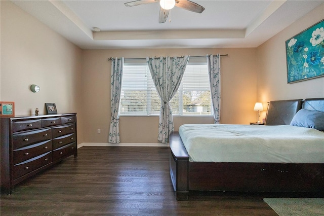 bedroom with ceiling fan, baseboards, a raised ceiling, and wood finished floors