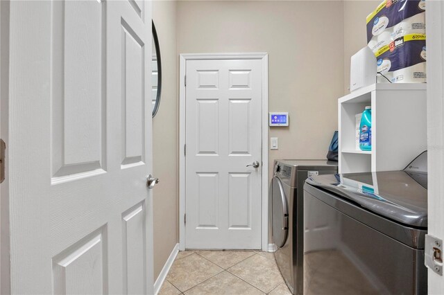 clothes washing area featuring laundry area, washer and clothes dryer, baseboards, and light tile patterned floors