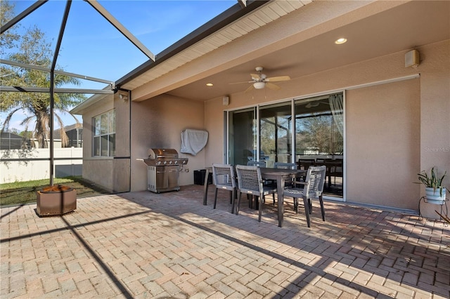 view of patio with ceiling fan, a lanai, a grill, fence, and outdoor dining area