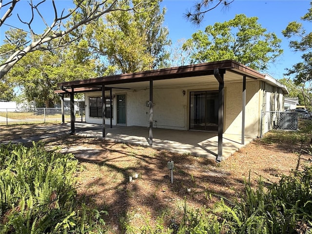 rear view of property featuring a patio, fence, and stucco siding