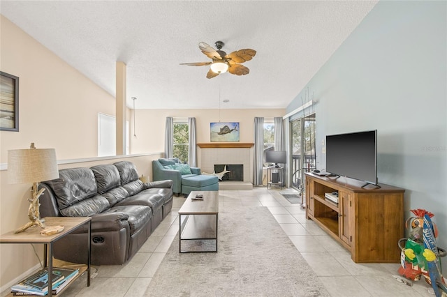 living area featuring ceiling fan, plenty of natural light, a textured ceiling, and light tile patterned floors