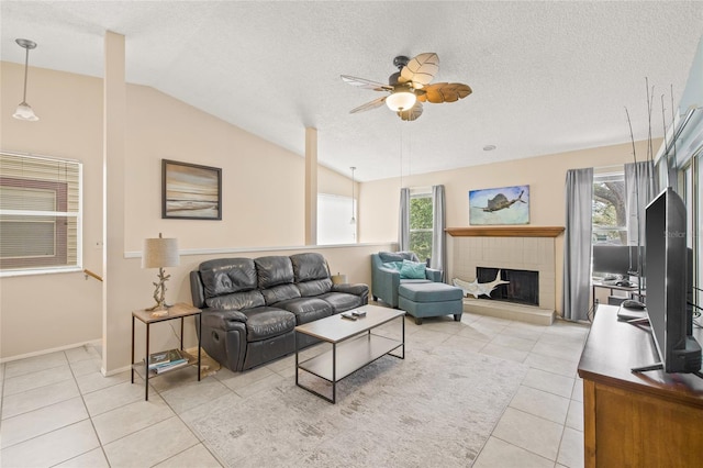 living room featuring a ceiling fan, lofted ceiling, a textured ceiling, a fireplace, and light tile patterned flooring