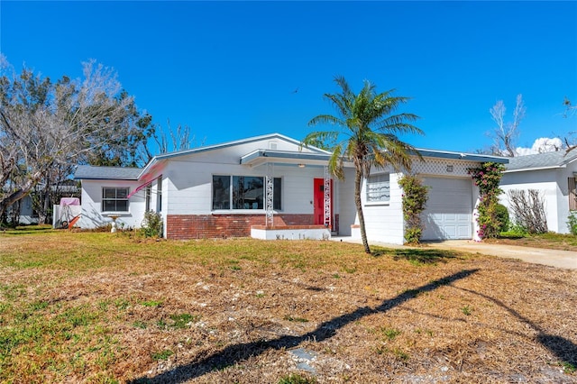 ranch-style home with an attached garage, a front lawn, concrete driveway, and brick siding