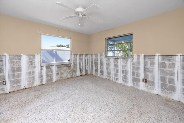 unfurnished room with ceiling fan, a wealth of natural light, and speckled floor