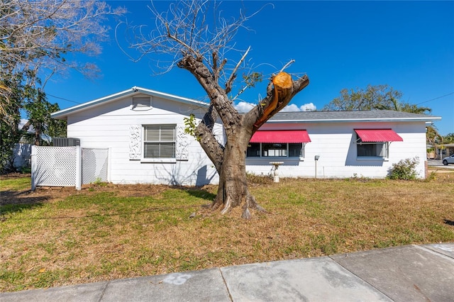 view of side of home featuring a lawn and fence