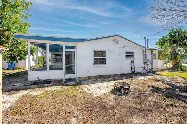 back of property with an outdoor fire pit and a sunroom