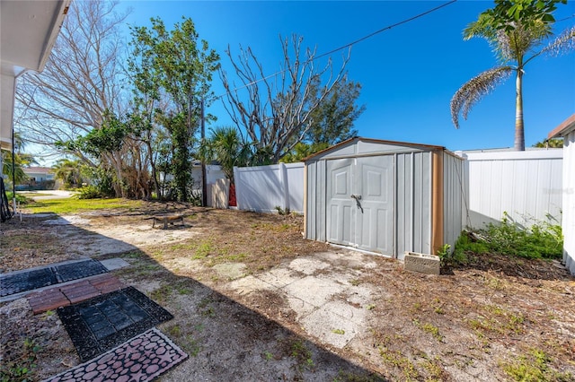 view of yard with a storage shed, a fenced backyard, and an outbuilding