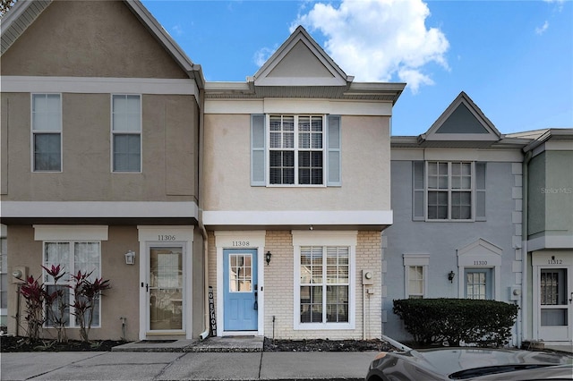 townhome / multi-family property with brick siding and stucco siding