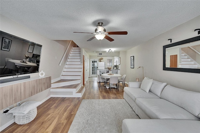 living room featuring baseboards, stairway, a textured ceiling, and wood finished floors