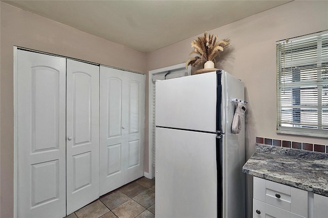 kitchen featuring freestanding refrigerator, white cabinets, and light tile patterned flooring