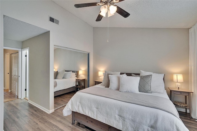 bedroom with visible vents, ceiling fan, vaulted ceiling, a textured ceiling, and wood finished floors