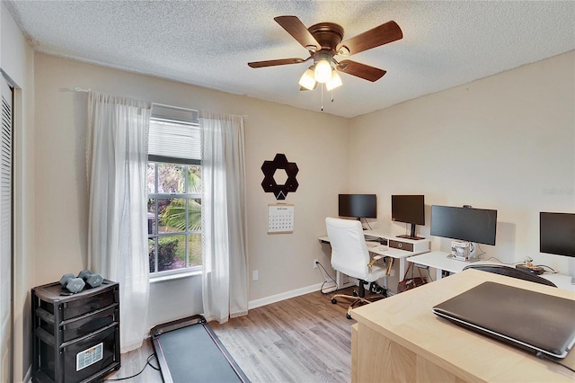 office with a textured ceiling, ceiling fan, light wood-style flooring, and baseboards