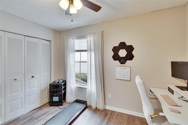 home office featuring a ceiling fan, a textured ceiling, baseboards, and wood finished floors