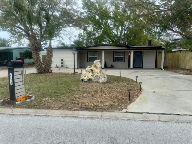 ranch-style house featuring concrete driveway and fence