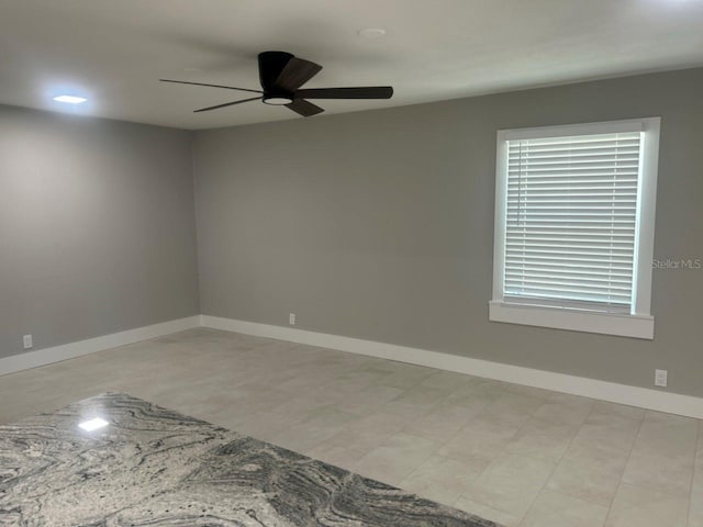 spare room with ceiling fan and baseboards