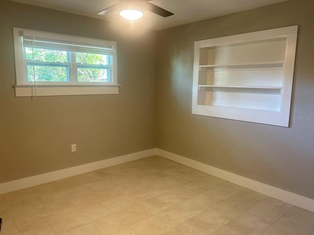 unfurnished room featuring built in shelves, a ceiling fan, and baseboards