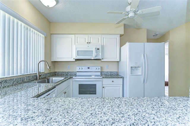 kitchen featuring white appliances, a textured ceiling, white cabinets, and a sink