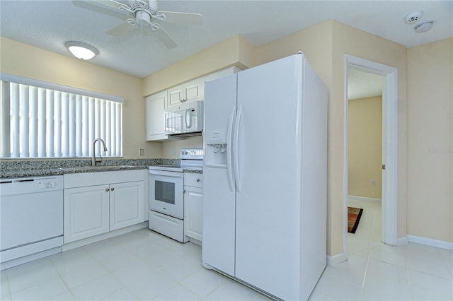 kitchen with white appliances, a sink, a ceiling fan, baseboards, and white cabinets