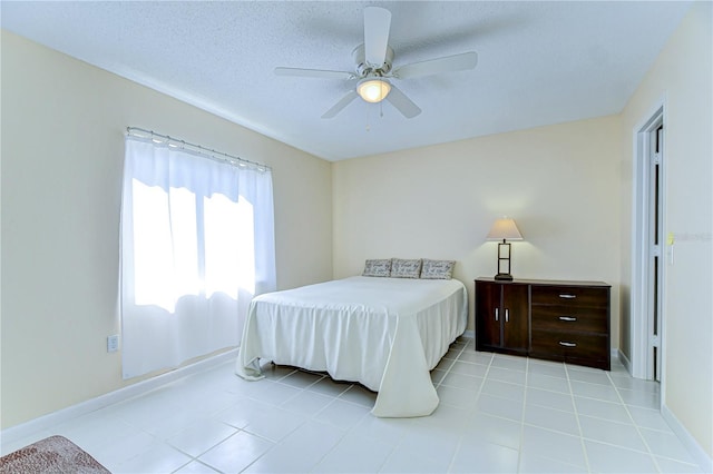 bedroom featuring a textured ceiling, ceiling fan, light tile patterned flooring, and baseboards