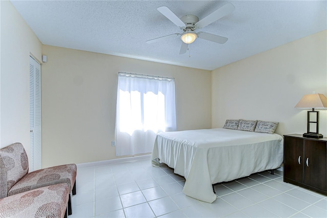 bedroom featuring a textured ceiling, ceiling fan, and light tile patterned flooring