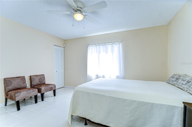 bedroom featuring a closet, ceiling fan, a textured ceiling, and light tile patterned floors