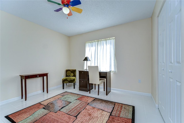 office space featuring baseboards, a ceiling fan, a textured ceiling, and tile patterned floors