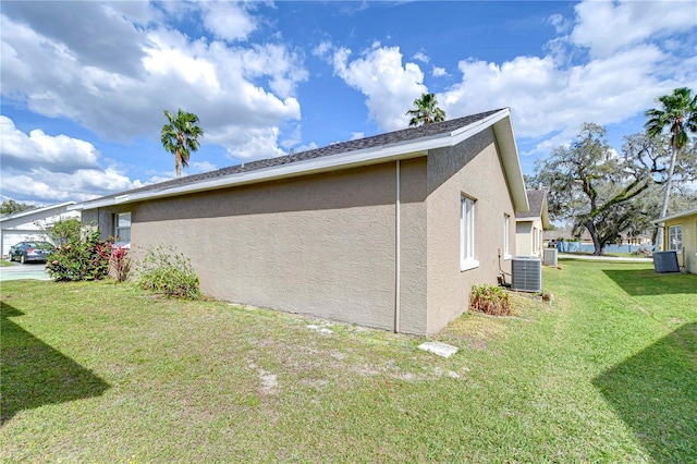 view of side of home featuring a yard, central AC unit, and stucco siding