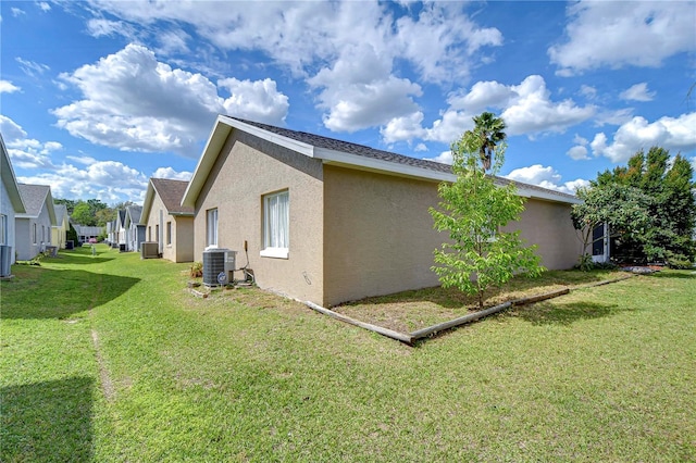 view of home's exterior with central AC unit, a lawn, and stucco siding