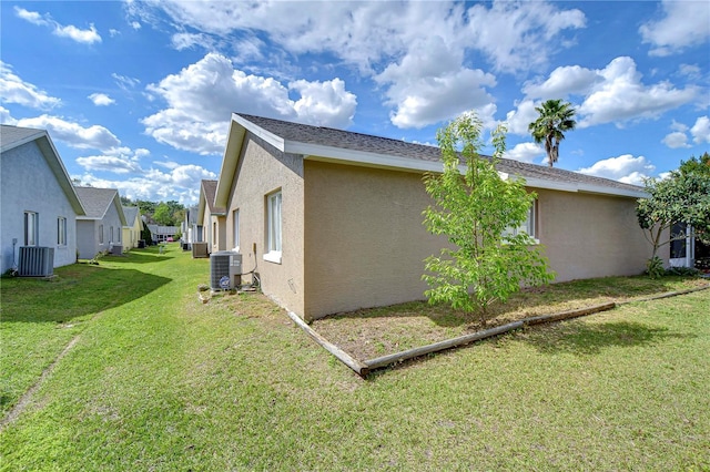 view of side of home featuring a yard, central air condition unit, and stucco siding