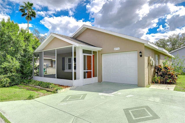 ranch-style home with an attached garage, a sunroom, concrete driveway, and stucco siding