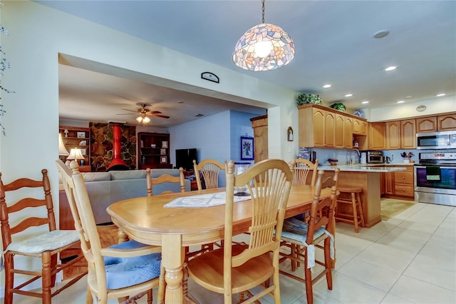 dining room featuring ceiling fan, light tile patterned floors, a wood stove, and recessed lighting