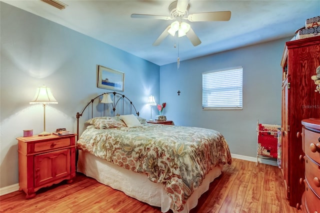 bedroom featuring baseboards, a ceiling fan, visible vents, and light wood-style floors