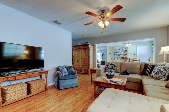 living room with baseboards, ceiling fan, visible vents, and wood finished floors