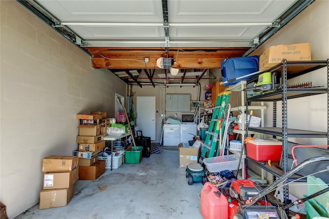 garage with a garage door opener, concrete block wall, and separate washer and dryer