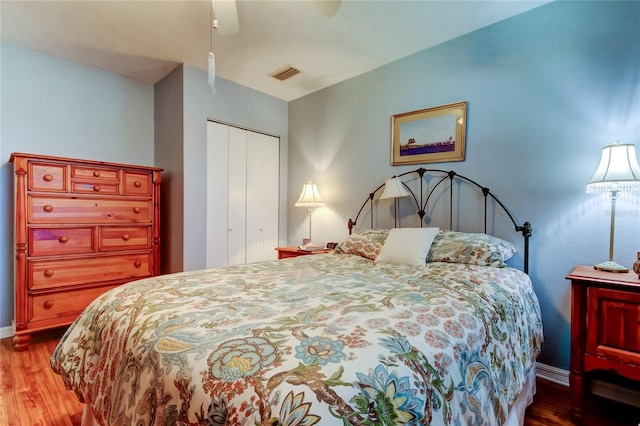 bedroom featuring ceiling fan, wood finished floors, visible vents, baseboards, and a closet