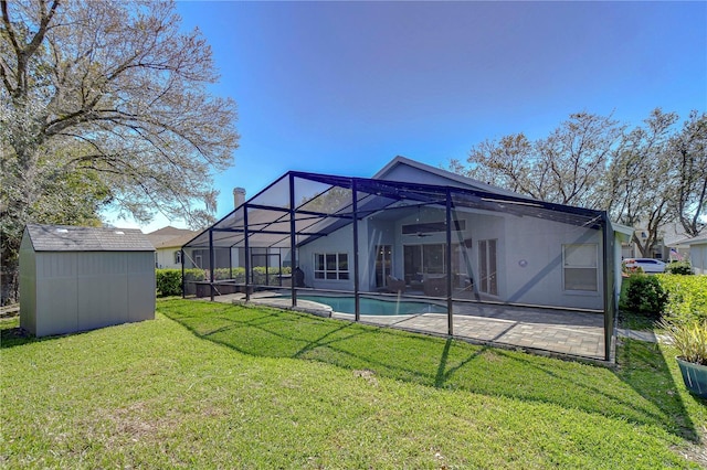 rear view of house with an outbuilding, a yard, a storage shed, glass enclosure, and a patio area