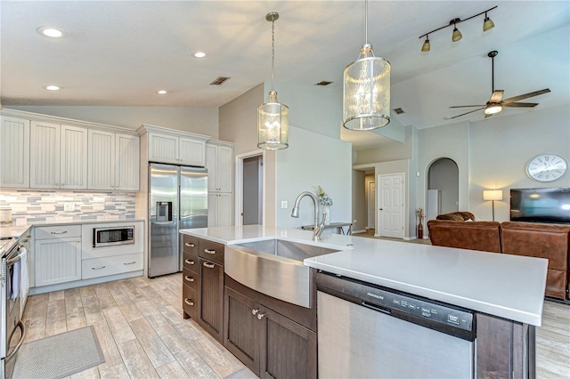 kitchen featuring stainless steel appliances, lofted ceiling, light countertops, decorative backsplash, and a sink