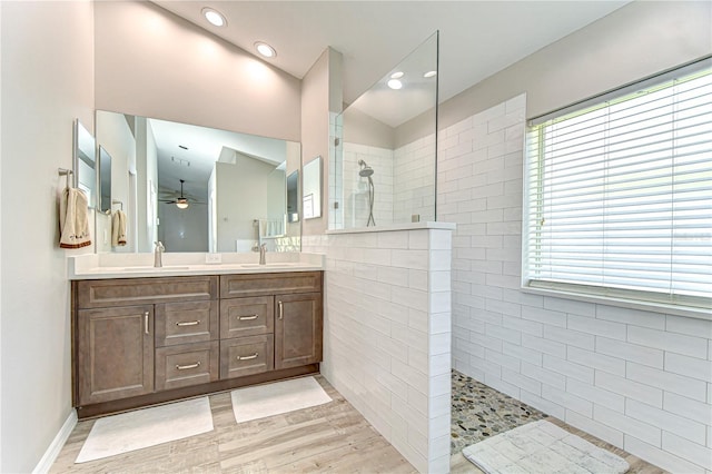 bathroom with double vanity, a ceiling fan, a walk in shower, and a sink