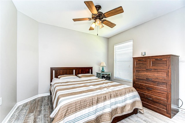 bedroom with ceiling fan, wood finished floors, and baseboards