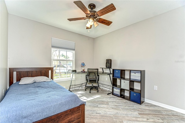 bedroom featuring ceiling fan, baseboards, and wood finished floors