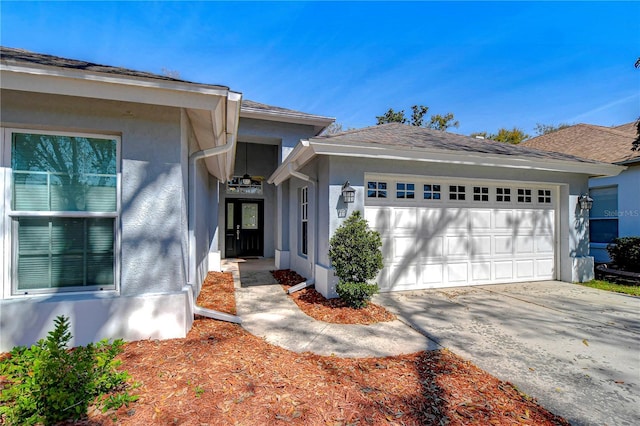 view of front of property featuring an attached garage, driveway, and stucco siding