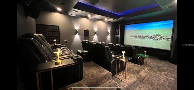 cinema room featuring carpet floors, a tray ceiling, and visible vents