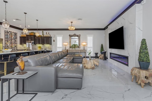 living area with marble finish floor, recessed lighting, crown molding, and a glass covered fireplace